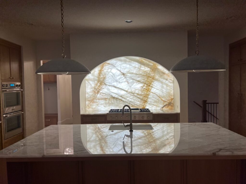 Backlit Cristallo Quartzite kitchen backsplash niche with warm LED lighting at the Manville Residence in Milton, Georgia