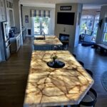 Dual backlit Cristallo Quartzite kitchen islands illuminated with custom frameless LED light panels at the Dowdie Residence in Braselton, Georgia.